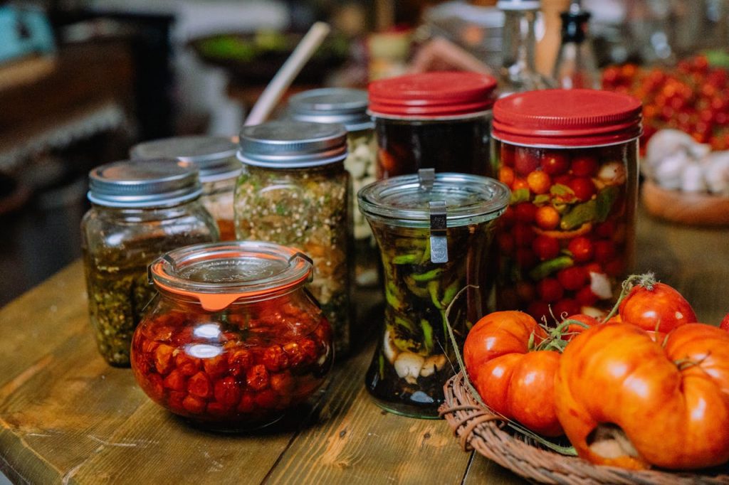 Colorful jars of homemade preserved vegetables and pickles on a rustic wooden table.